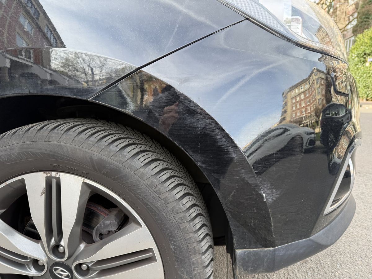 Radlaufkante desselben schwarzen SUV, Lack bis auf die Grundierung abgetragen