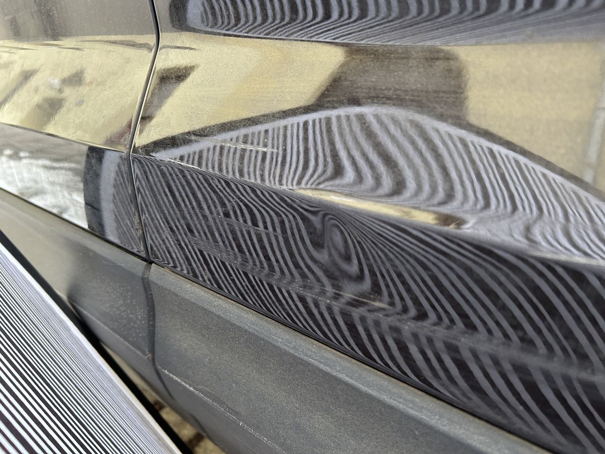 Eingedrückte Fläche über zwei Türen eines dunklen SUV, Akte mit 18.022,68 Euro Schadenhöhe